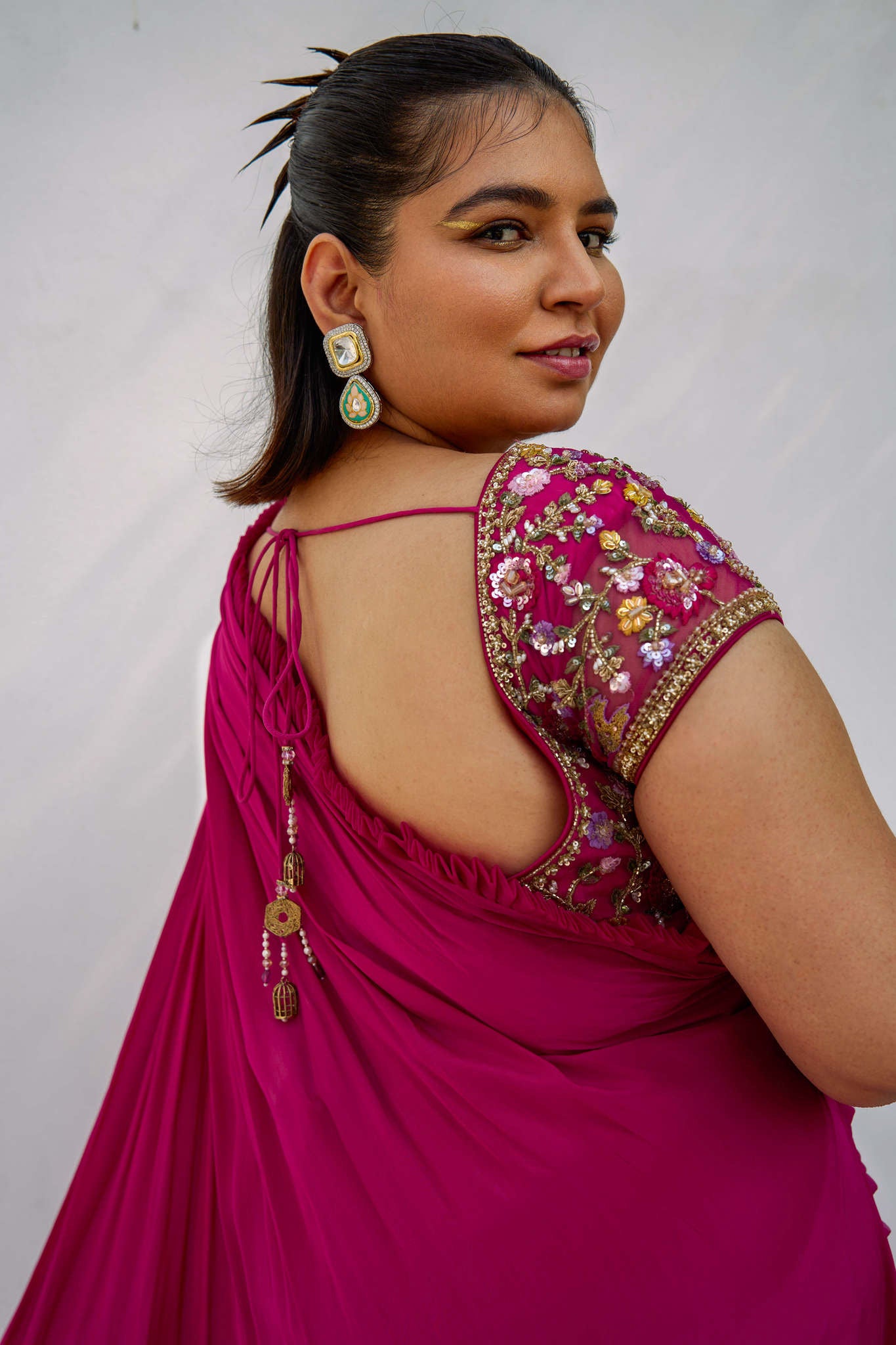This outfit features a high-waisted skirt with attached wrap-around draping - all pre-stitched so you can put the outfit together in 30 seconds or less. The piece is paired with a pink hand-embroidered, cap-sleeve blouse with a low