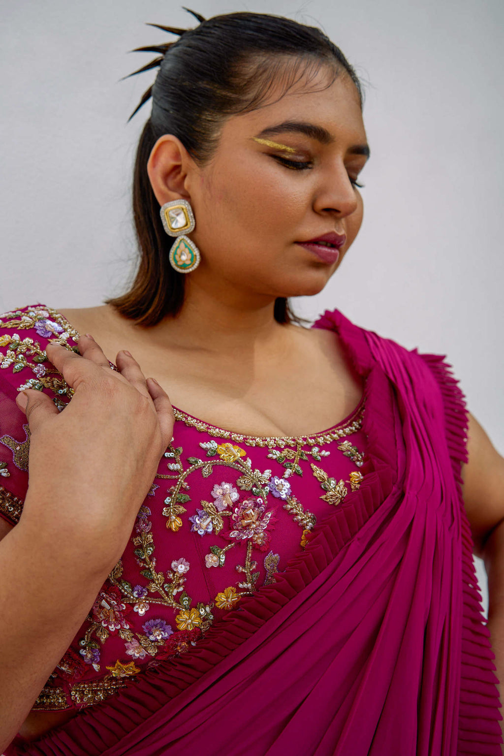 This outfit features a high-waisted skirt with attached wrap-around draping - all pre-stitched so you can put the outfit together in 30 seconds or less. The piece is paired with a pink hand-embroidered, cap-sleeve blouse with a low