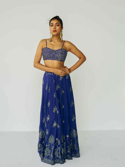 A woman wearing a bright blue embroidered top and skirt with embroidered dupatta.