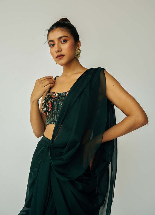 The Adya Drape Saree makes it easy to get the saree look without any pleating and features a shiny organaza skirt with an attached drape + a hand embroidered, bustier top. 
