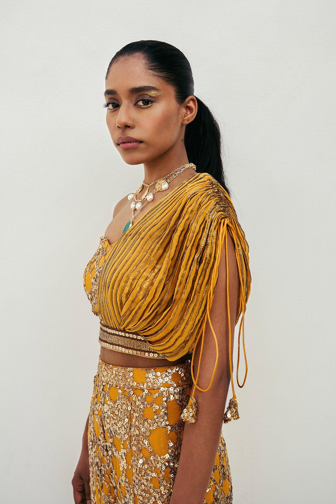The sequined Tanvi Palazzo Set consists of a one-shoulder adjustable top and flared palazzo pants.