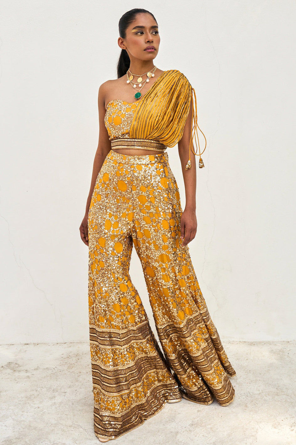 The sequined Tanvi Palazzo Set consists of a one-shoulder adjustable top and flared palazzo pants.