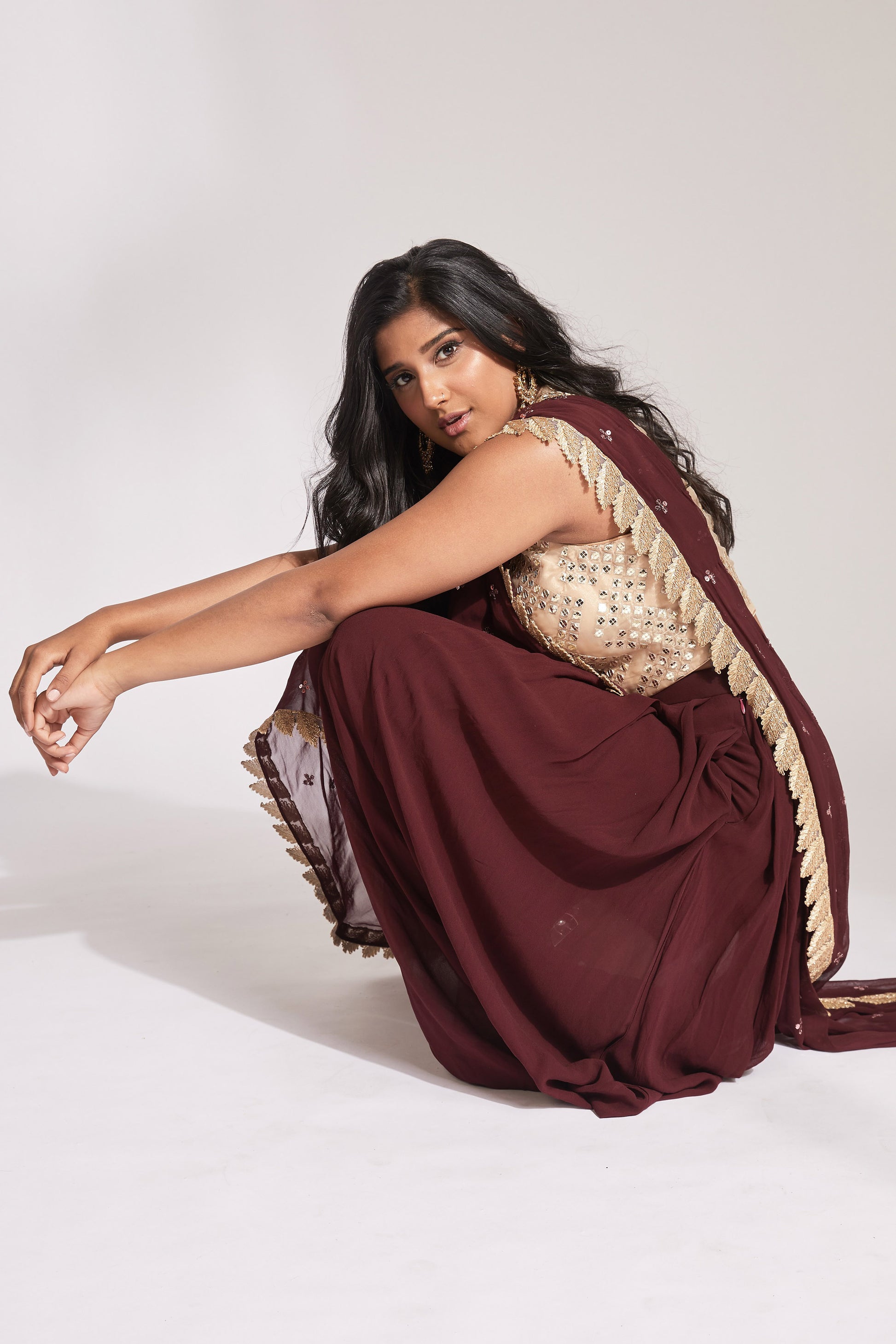 The Tara Dhoti takes the elegance of a saree's drape and combines it with the comfort of a dhoti pant. The booti-work drape is attached to the outfit and is paired with a mirror work blouse.