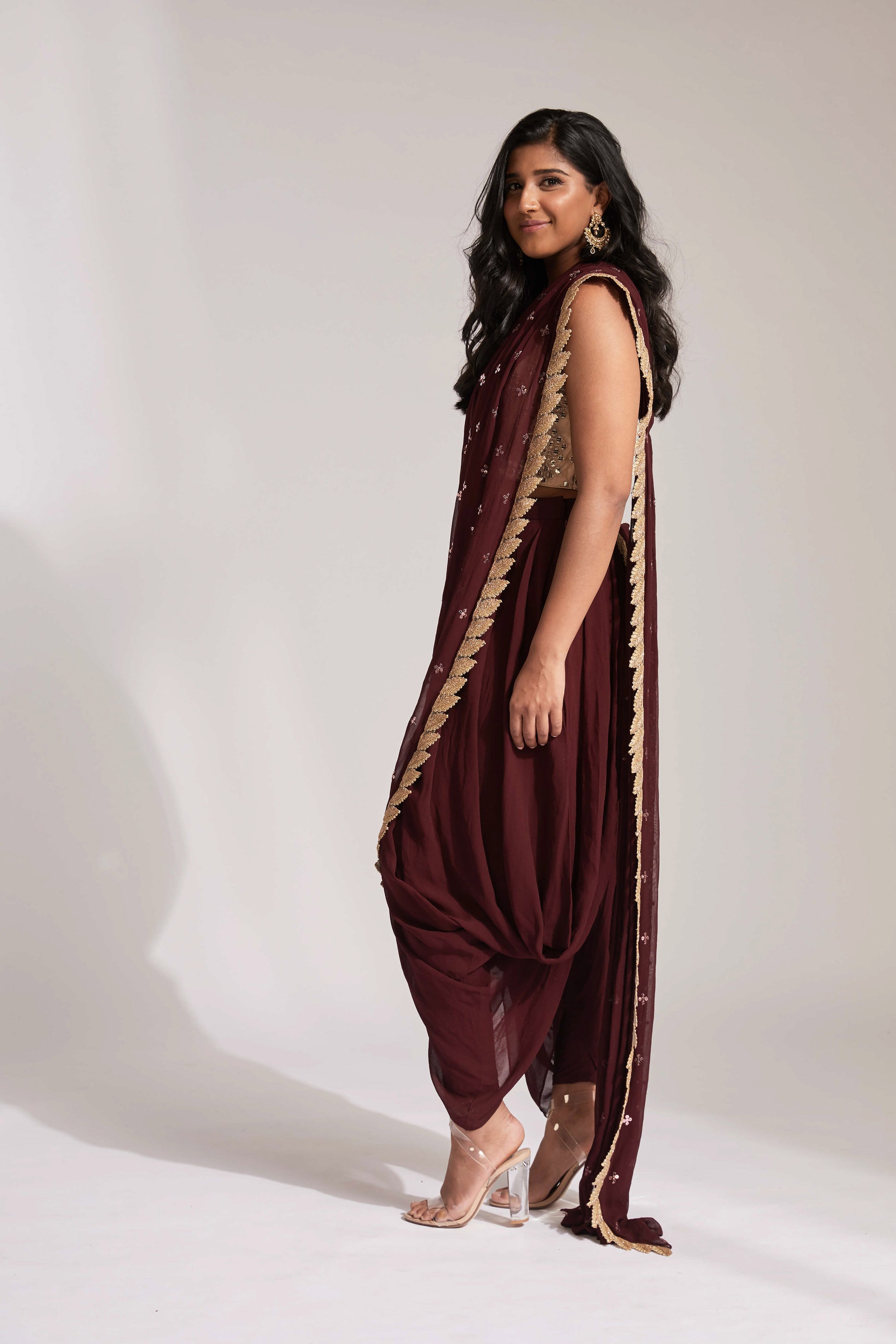 The Tara Dhoti takes the elegance of a saree's drape and combines it with the comfort of a dhoti pant. The booti-work drape is attached to the outfit and is paired with a mirror work blouse.