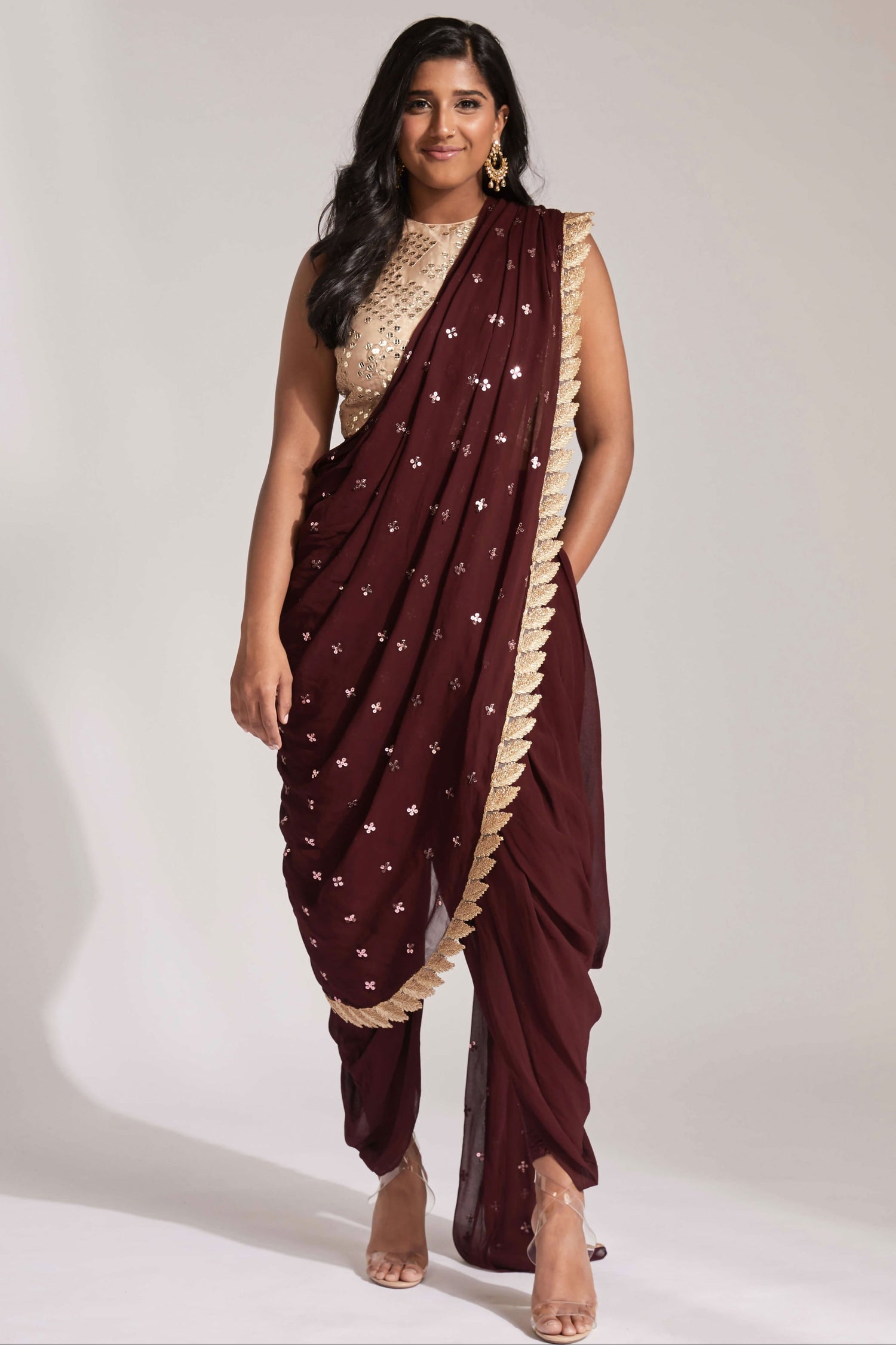 The Tara Dhoti takes the elegance of a saree's drape and combines it with the comfort of a dhoti pant. The booti-work drape is attached to the outfit and is paired with a mirror work blouse.