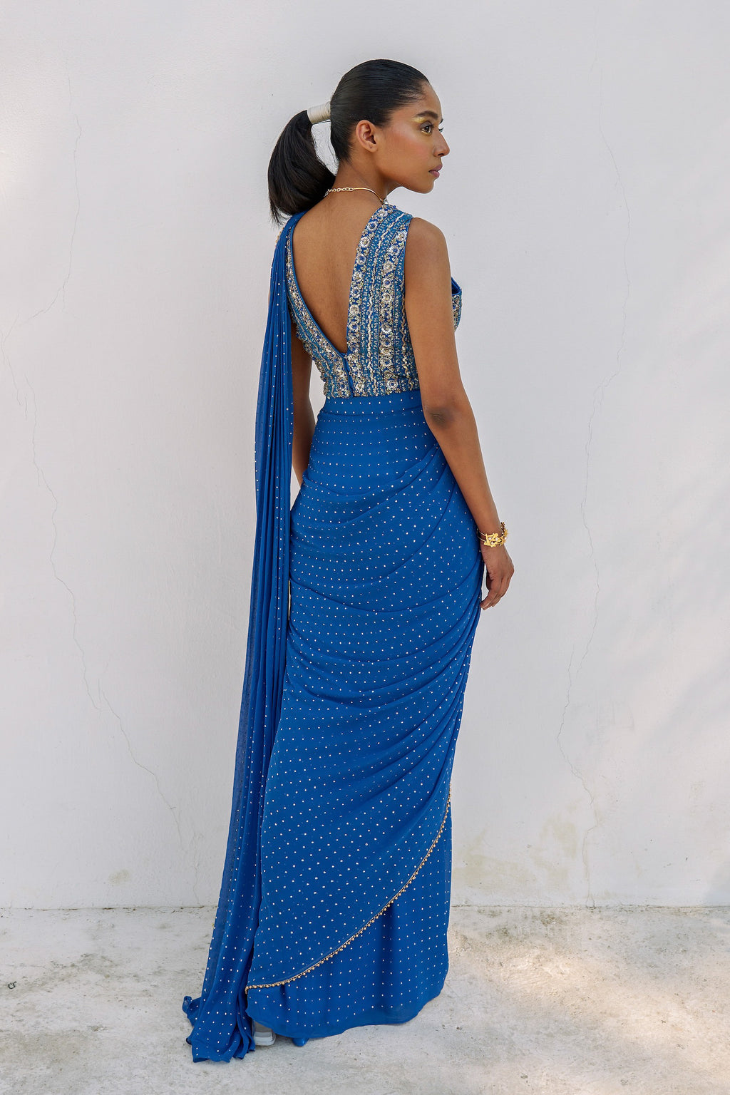 This outfit features a skirt with attached wrap-around draping - all pre-stitched so you can put the outfit together in 30 seconds or less. The drape has small gold embellishments throughout and the piece is paired with a gold hand-embroidered v-neck blouse.