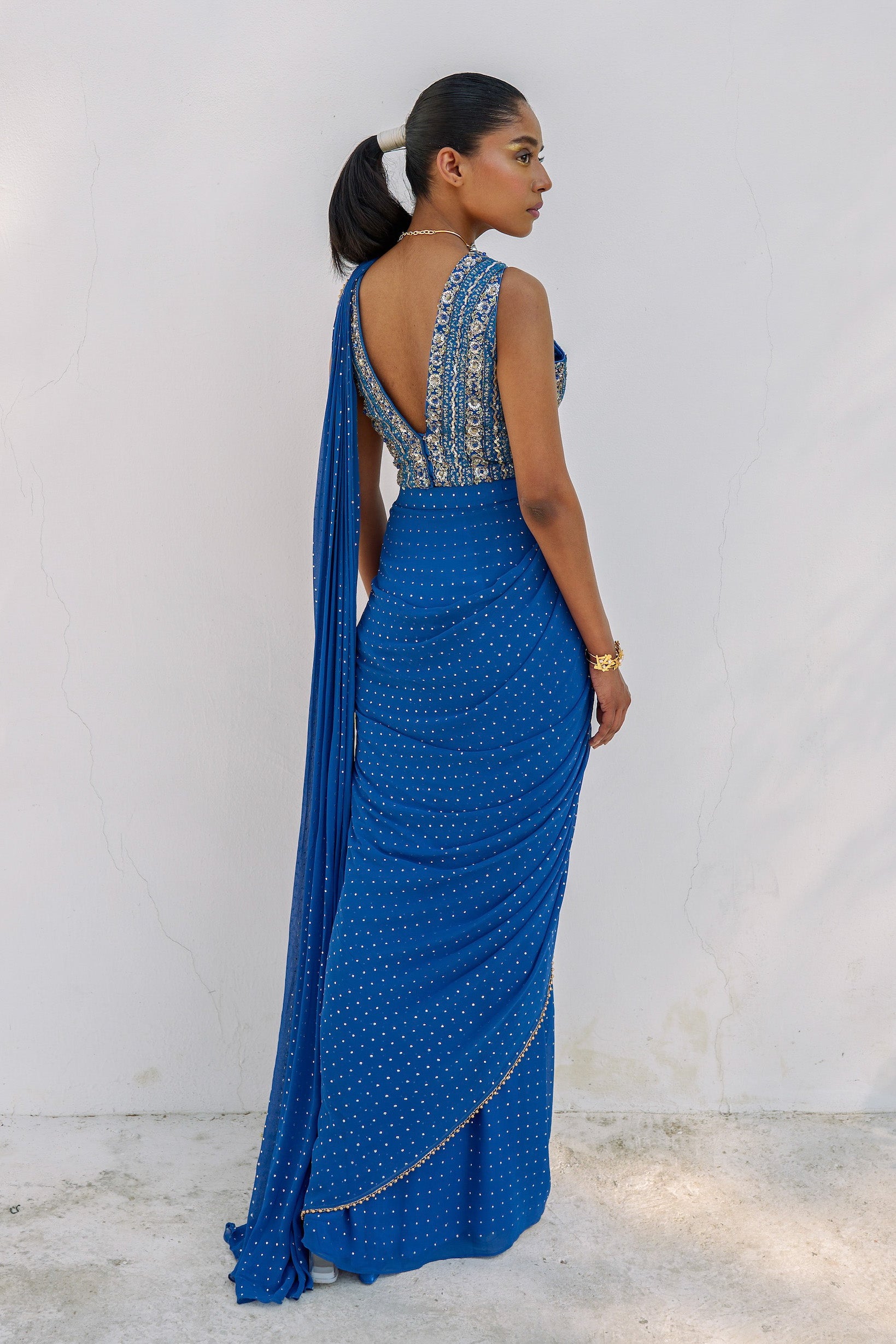 This outfit features a skirt with attached wrap-around draping - all pre-stitched so you can put the outfit together in 30 seconds or less. The drape has small gold embellishments throughout and the piece is paired with a gold hand-embroidered v-neck blouse.