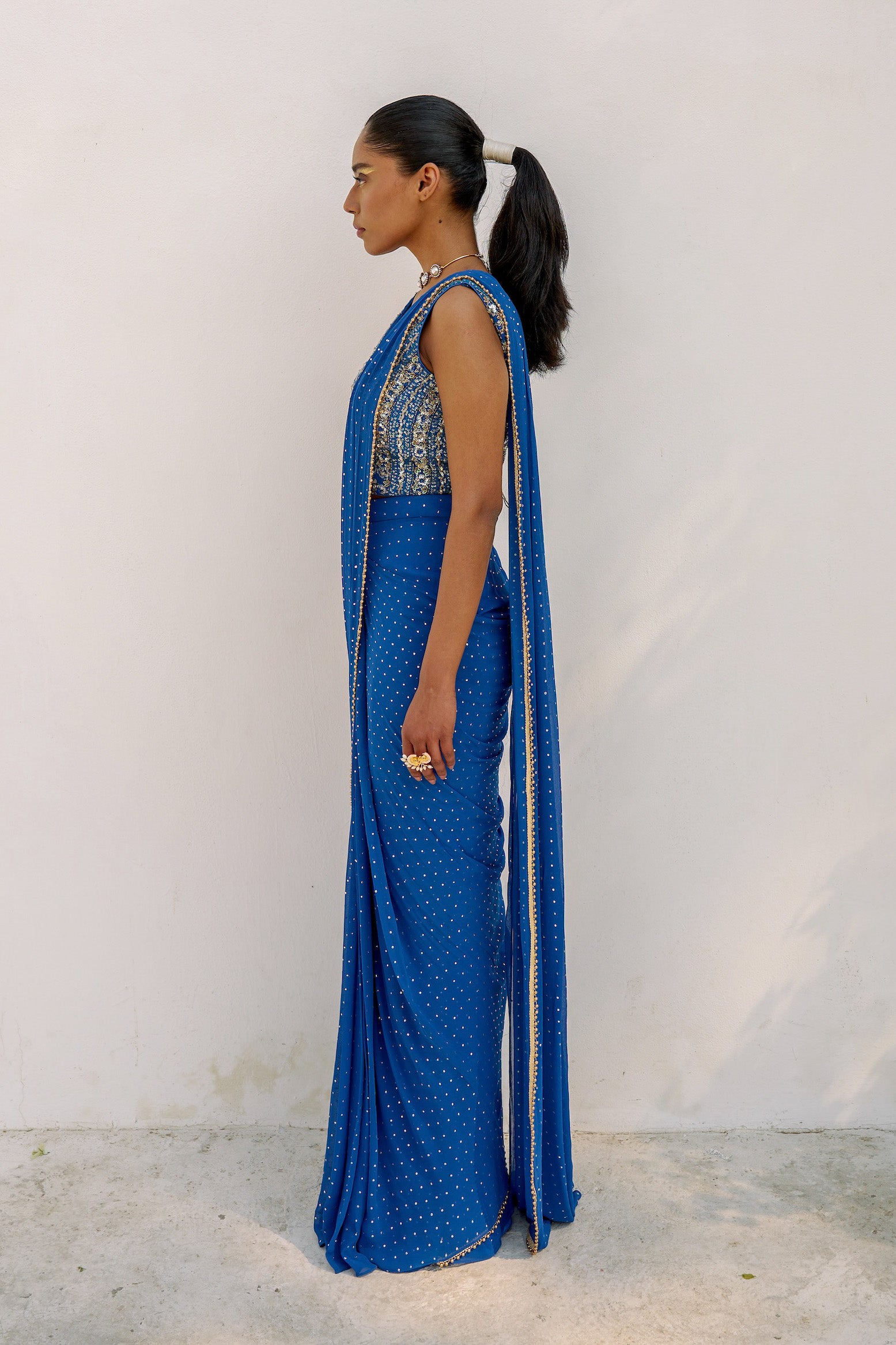 This outfit features a skirt with attached wrap-around draping - all pre-stitched so you can put the outfit together in 30 seconds or less. The drape has small gold embellishments throughout and the piece is paired with a gold hand-embroidered v-neck blouse.