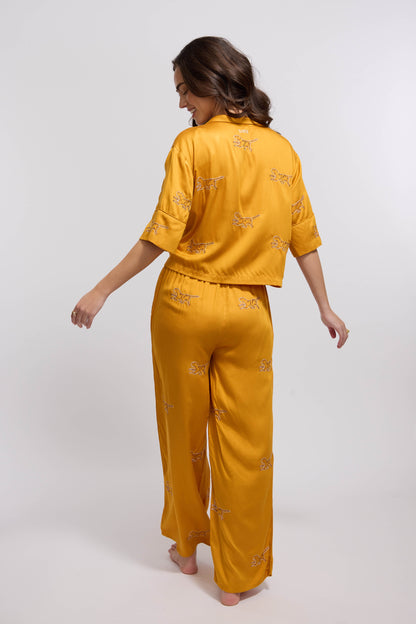 A woman wearing a marigold colored loungewear set with tiger embroidery.