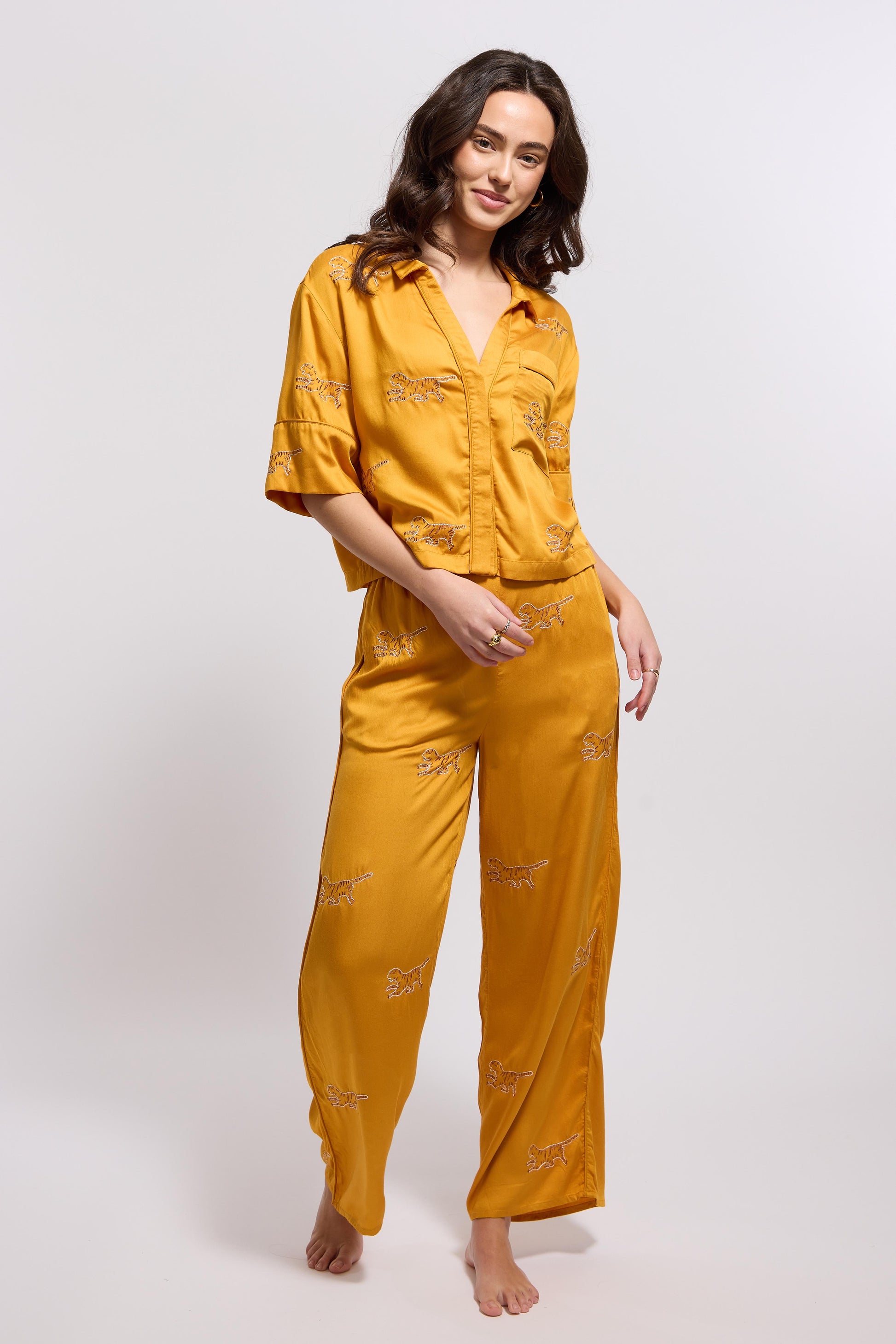 A woman wearing a marigold colored loungewear set with tiger embroidery.