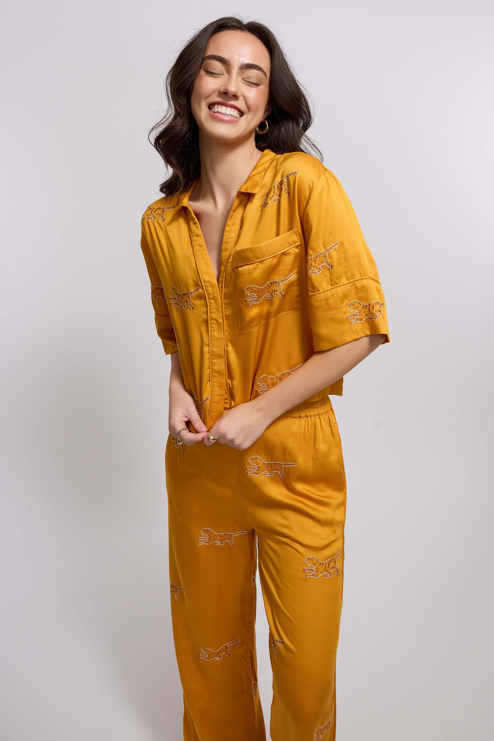 A woman wearing a marigold colored loungewear set with tiger embroidery.