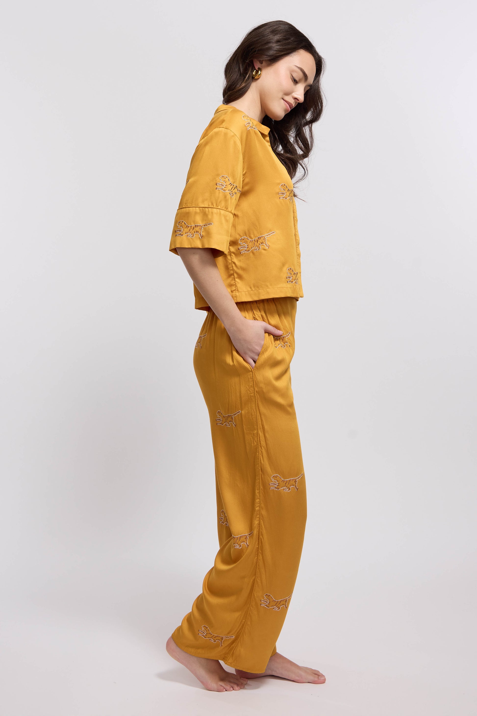 A woman wearing a marigold colored loungewear set with tiger embroidery.