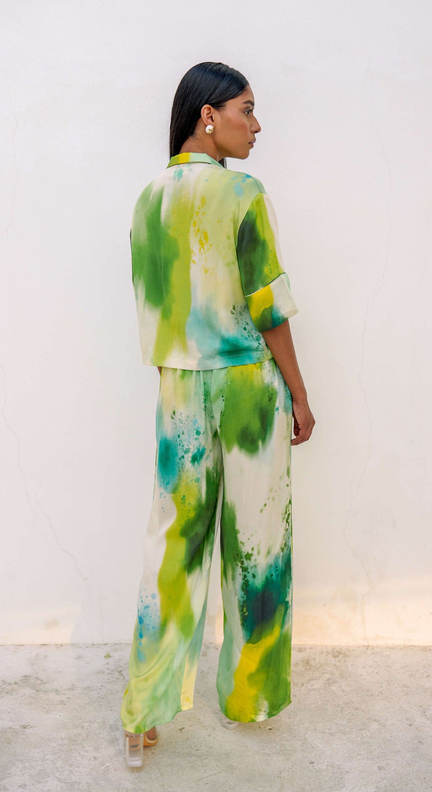 Woman in a multi-colored green printed loungewear set with clear heels. 